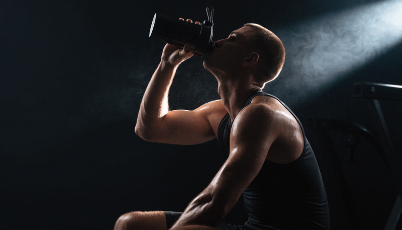 Atleet drinkt shake direct na training in donkere gym, obsidian merkstijl