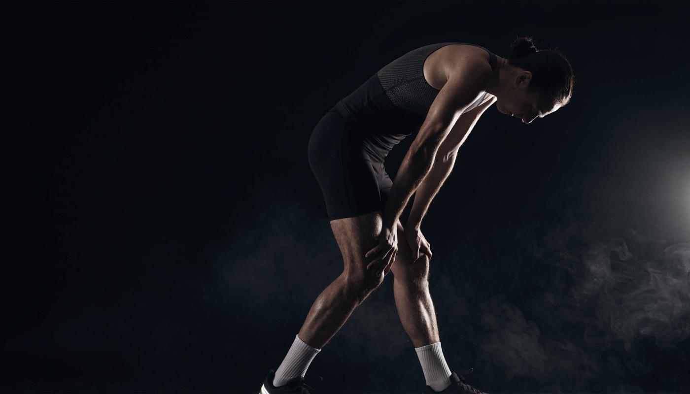 Atleet ademt zwaar na intensieve interval sprint, donkere obsidian gym sfeer met dramatisch licht