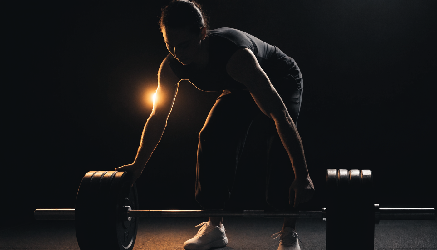 Atleet voegt gewichtsschijven toe aan een barbell, donkere obsidian sportschool sfeer