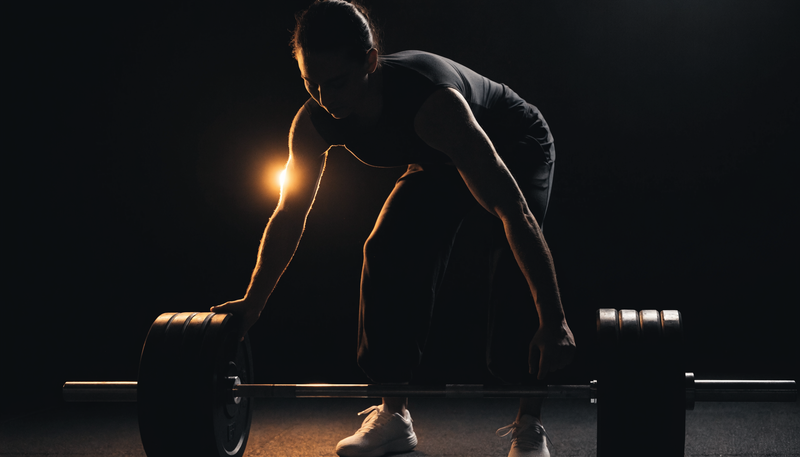 Atleet voegt gewichtsschijven toe aan een barbell, donkere obsidian sportschool sfeer