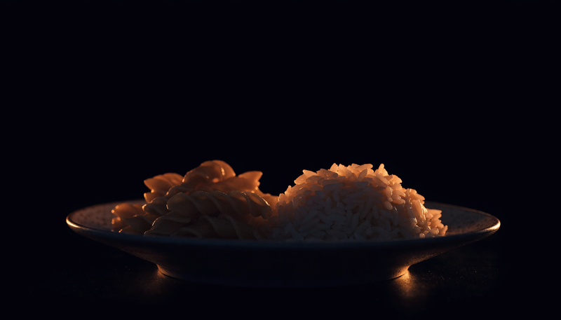 Bord met pasta en rijst als koolhydraatbron voor sporters, donkere obsidian foodstyling