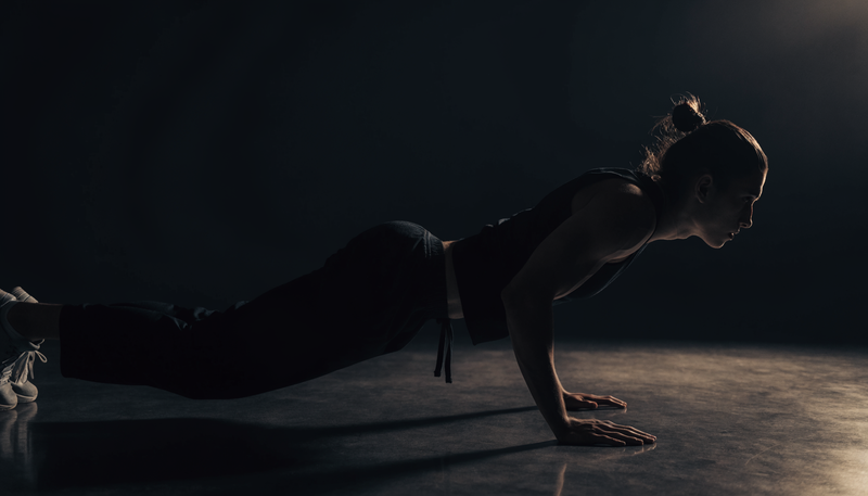 Atleet doet push-ups in een minimalistische donkere thuisomgeving, obsidian sfeer