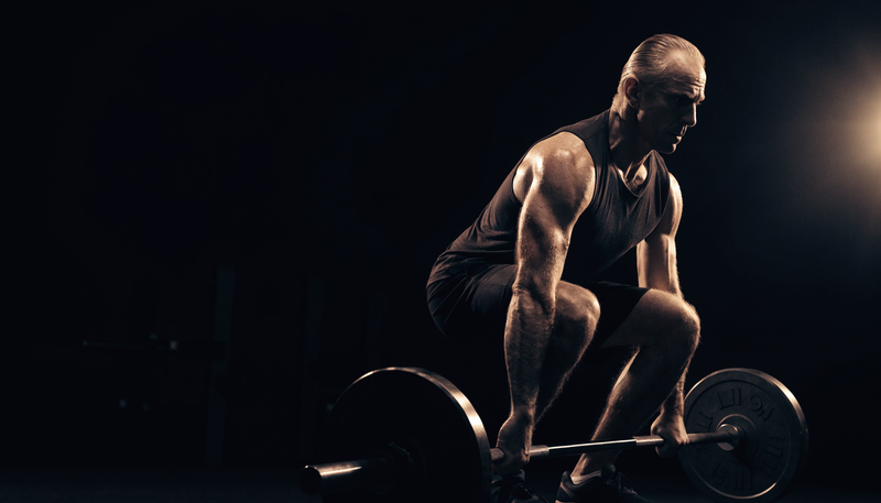 Atleet van middelbare leeftijd traint met kracht in donkere obsidian sportschool