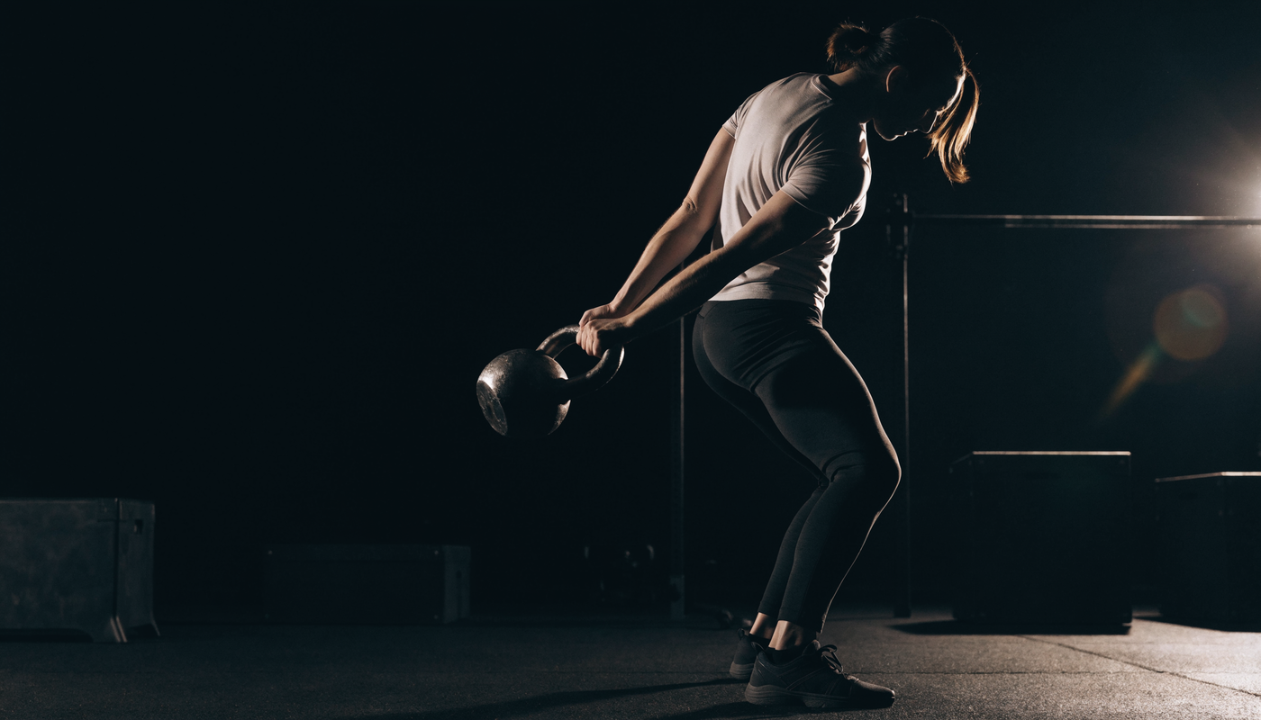 Atleet zwaait met een kettlebell in een donkere functionele fitness studio, obsidian merkstijl