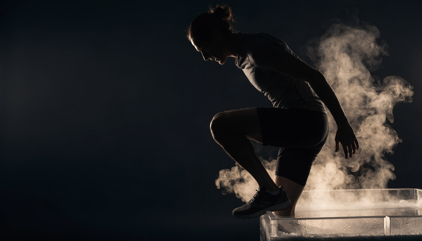 Atleet stapt in een ijsbad met stoom die opstijgt, dramatische donkere obsidian sfeer
